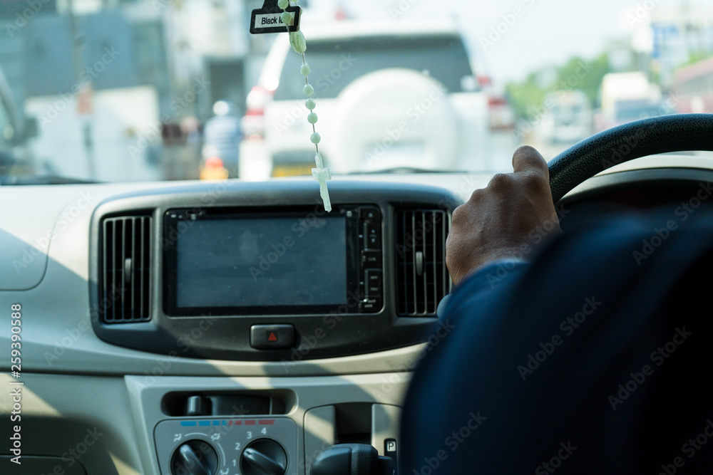 Men’s hand holding steering wheel of car while driving on the road