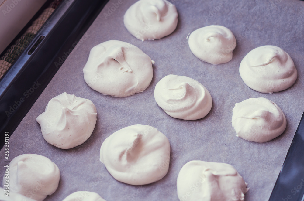 Home made meringues on a baking pan. Cooking a traditional french dessert 