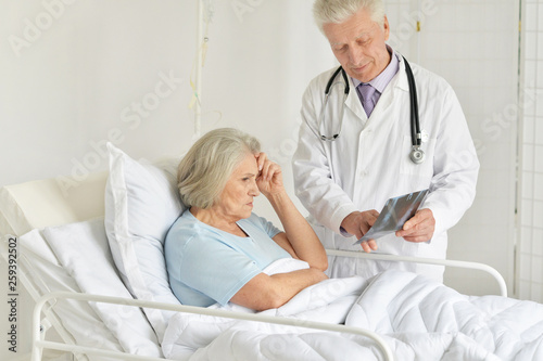 Portrait of sad senior woman in hospital with caring doctor