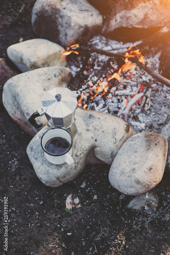 Cup hot coffee and coffee maker near to bonfire. Concept adventure active vacations outdoor. Summer camp