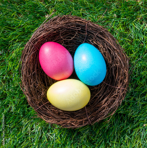 Three painted easter eggs in a nest on green grass