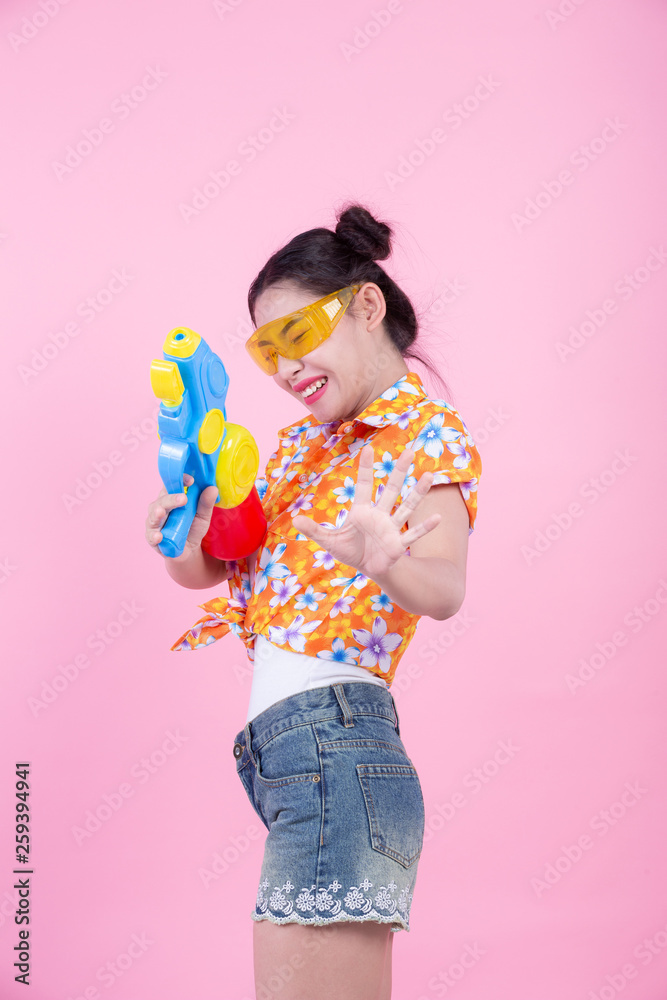 Happy girl holding a pink background water gun. Happy girl holding a pink background water gun.