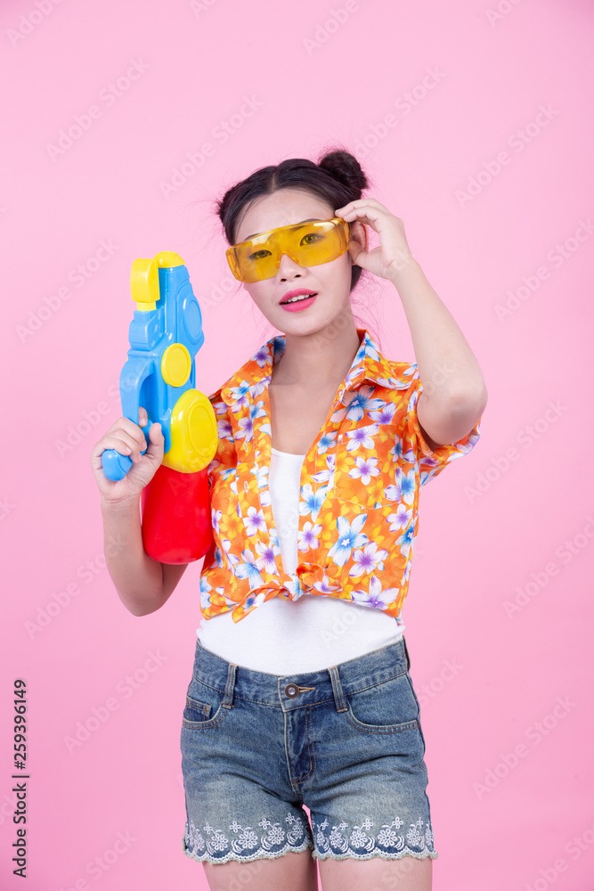 Happy girl holding a pink background water gun. Happy girl holding a pink background water gun.