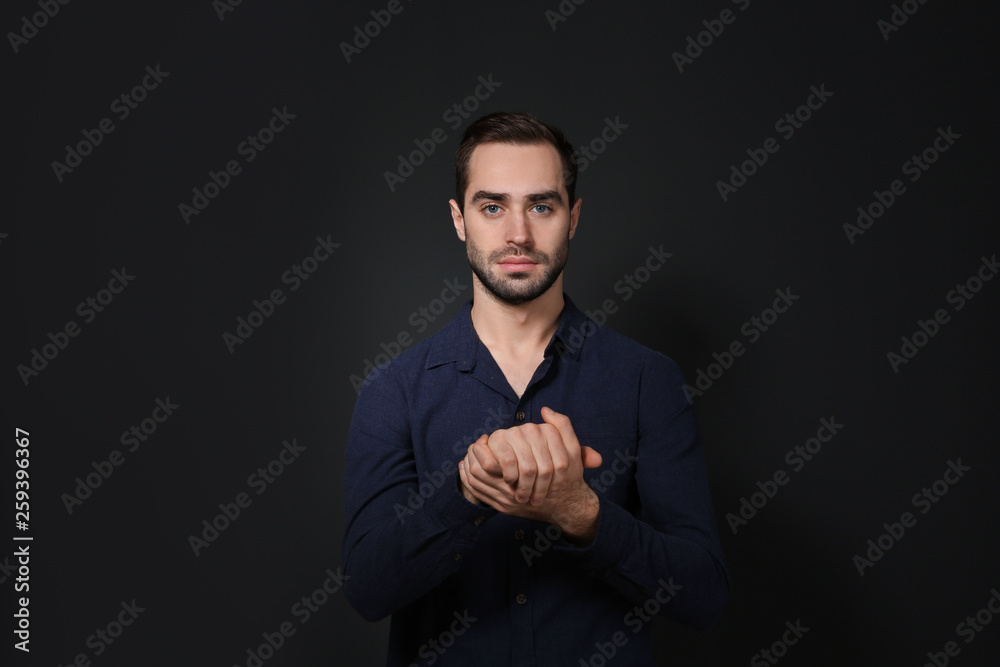 Man showing BELIEVE gesture in sign language on black background