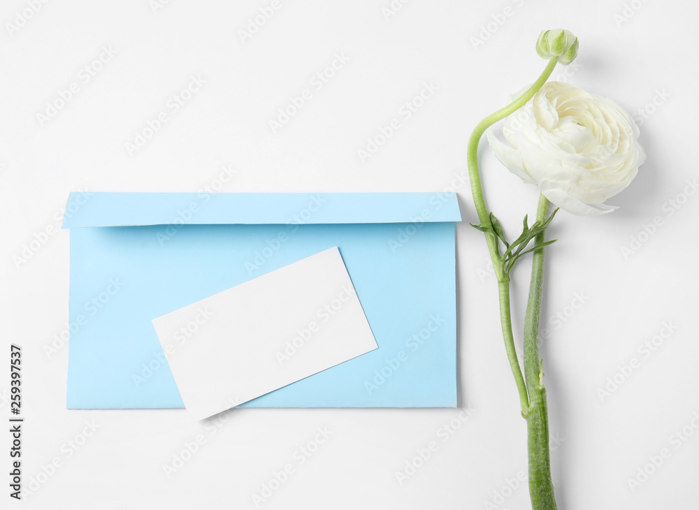 Envelope with card and beautiful ranunculus flower on white background, top view. Space for text