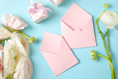Flat lay composition with beautiful ranunculus flowers and envelopes on color background