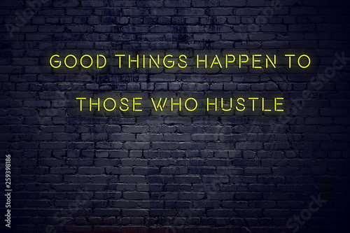 Positive inspiring quote on neon sign against brick wall good things happen to those who hustle
