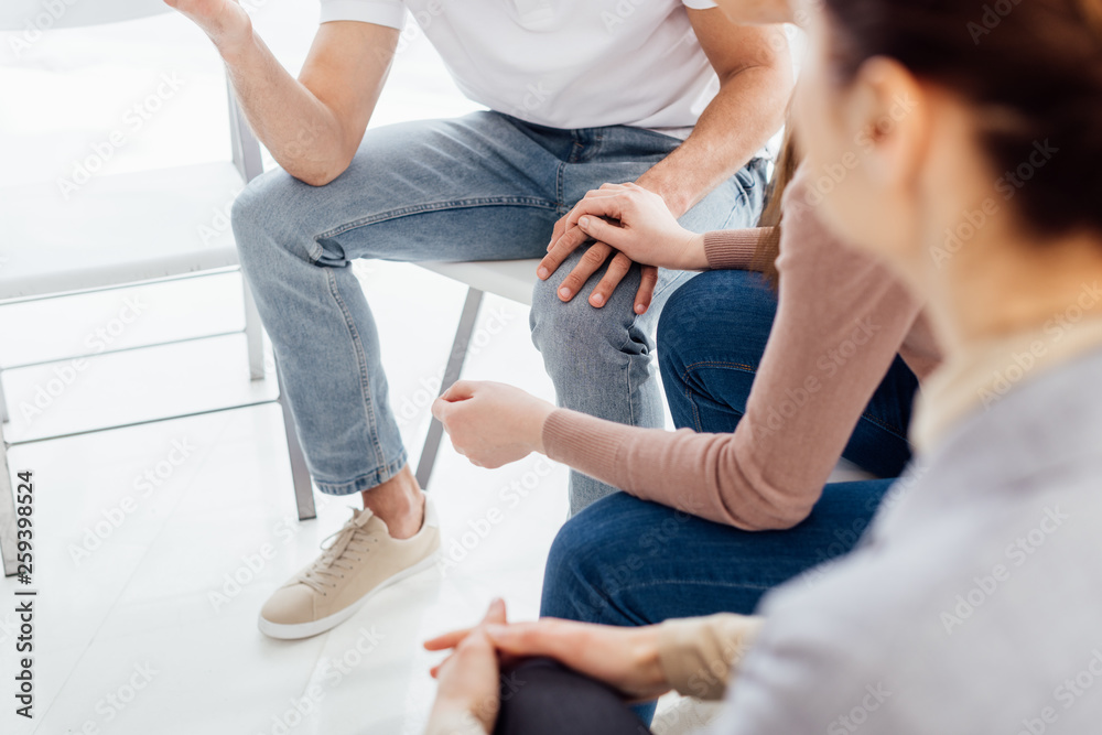 Fototapeta premium partial view of people sitting and holding hands during group therapy session