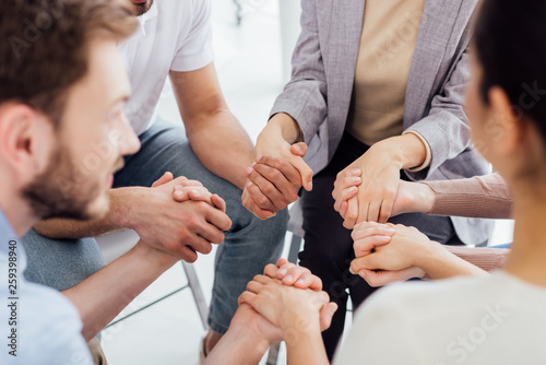 cropped view of people holding hands during group therapy session photo