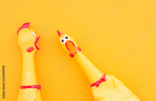 Surprised chicken toys are isolated on a orange background, one looks at the camera and shouts, the other one to the side. Screaming chicken toys on a yellow background. photo