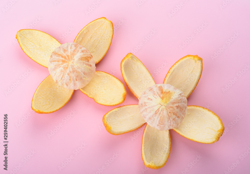 Two peeled oranges isolated on pink background. Orange peel as petals.