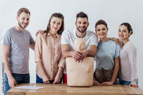 group of people with cpr dummy looking at camera and smiling during first aid training class photo