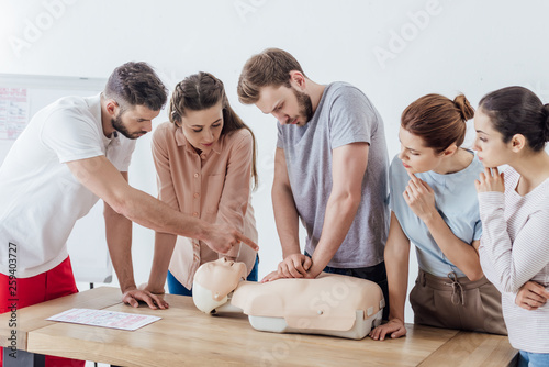 group of people with instructor performing cpr on dummy during first aid training photo