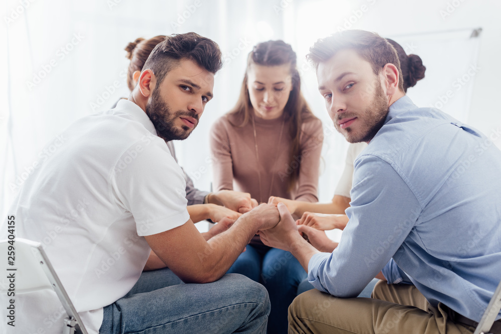 Obraz premium selective focus of group of people sitting and stacking hands during therapy session