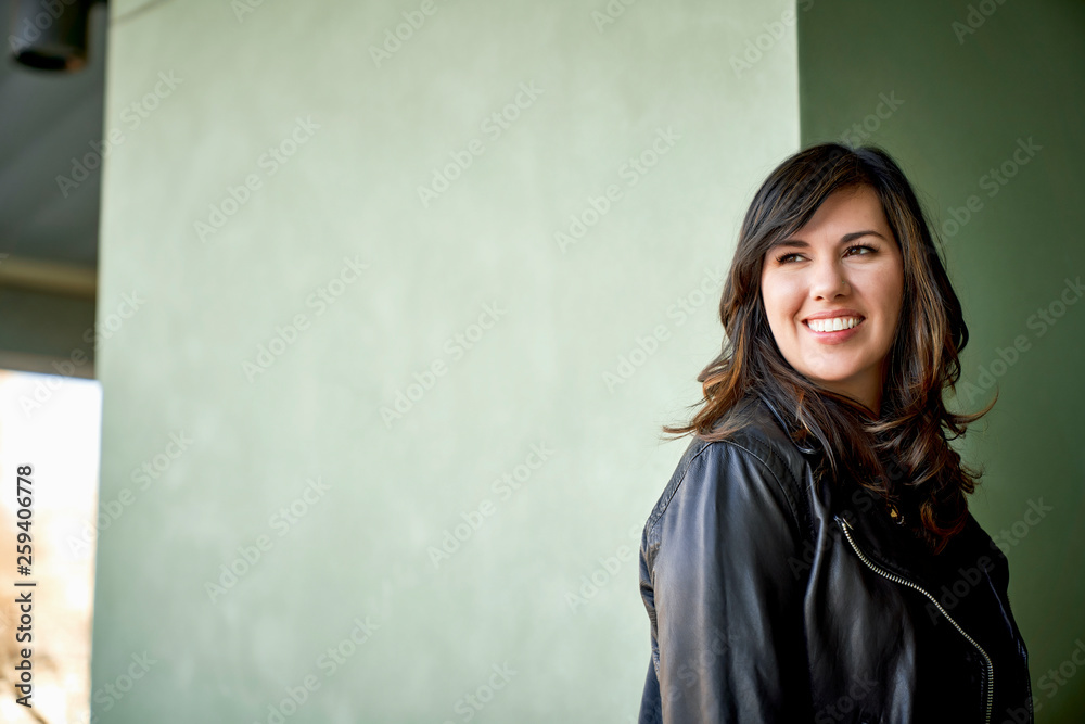 Smiling brunette woman standing against wall Smiling brunette woman standing against wall