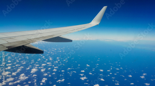 Airplane wing over beautiful cloud spotted ocean and sky.