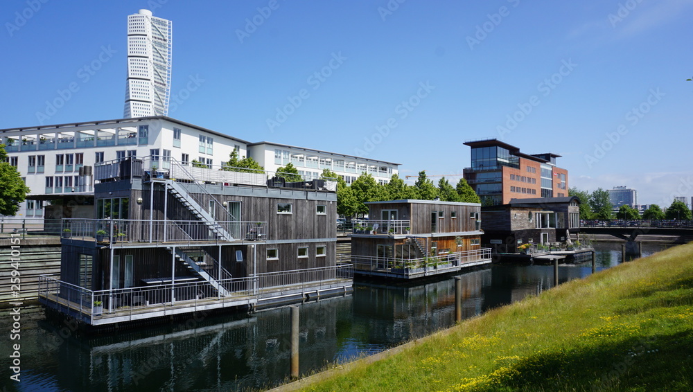 Docked houses on the river with a view of the Turning Torso in the background in Malmö, Sweden