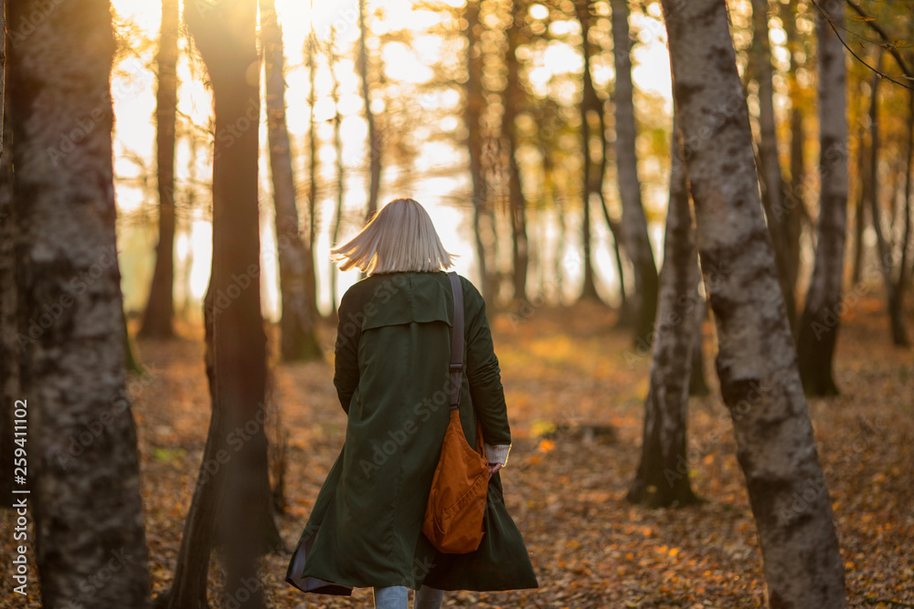 Rear view of woman with bleached hair walking in forest during sunset Rear view of woman with bleached hair walking in forest during sunset