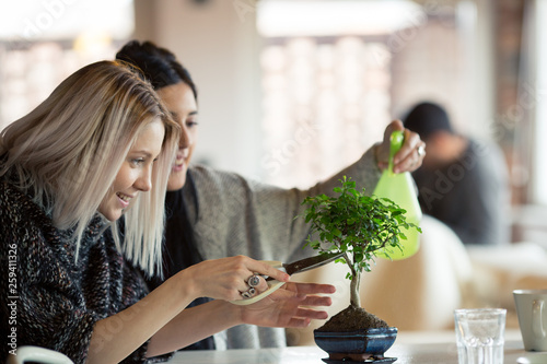 Smiling woman with bleached hair trimming houseplant indoors
