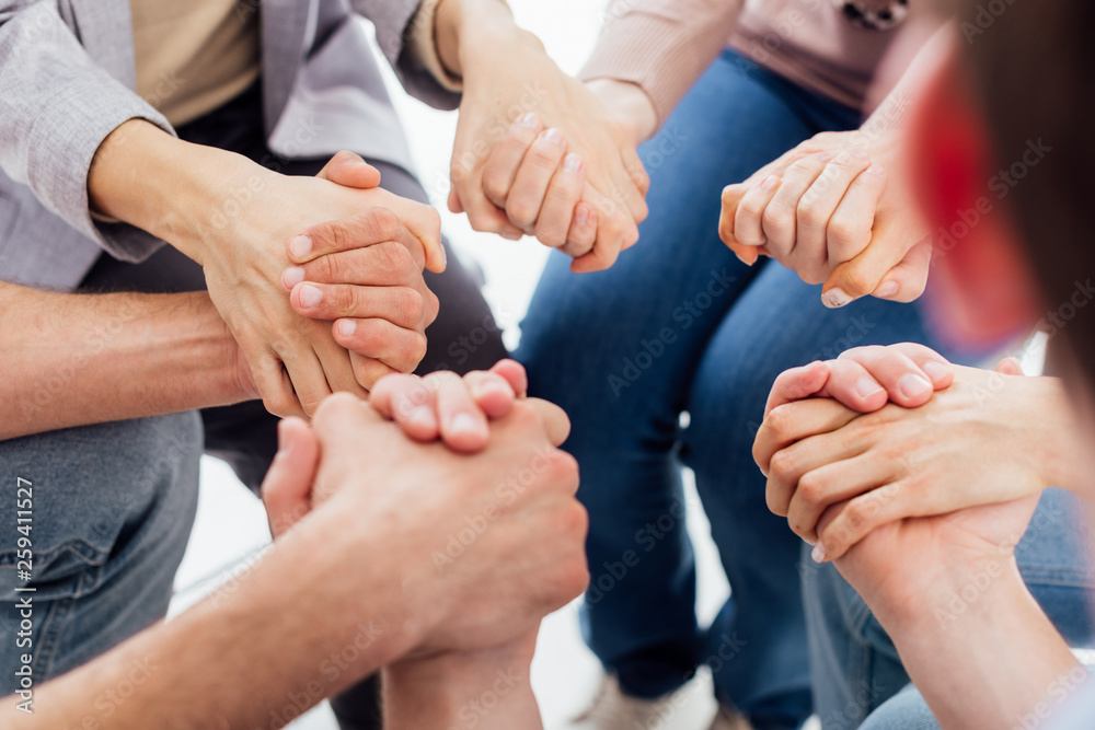 cropped view of people holding hands during group therapy session cropped view of people holding hands during group therapy session
