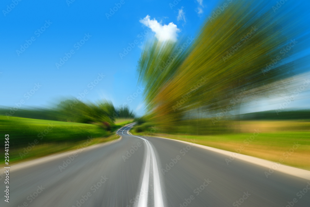 Road among green fields with motion blur effect
