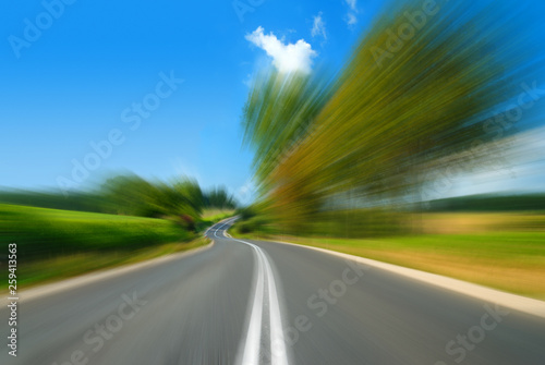 Road among green fields with motion blur effect