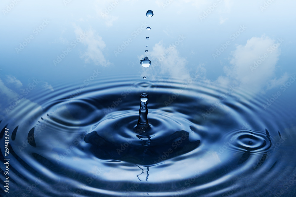 Falling drops of water with blue sky and white clouds in backgro Falling drops of water with blue sky and white clouds in backgro