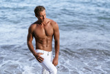 Portrait of sexy muscular man with bare-chested posing on camera at beach