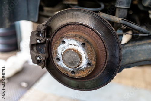 Rear brake discs with caliper and brake pads in the car, on a car lift in a workshop.