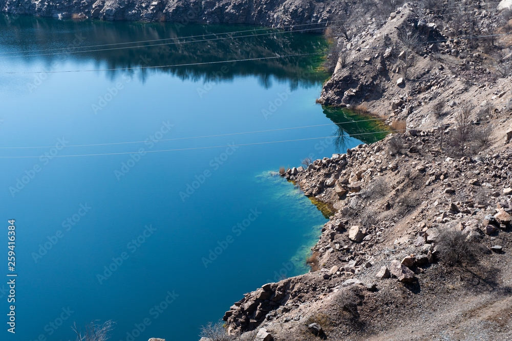 Steep bank of radon quarry lake with emerald water 