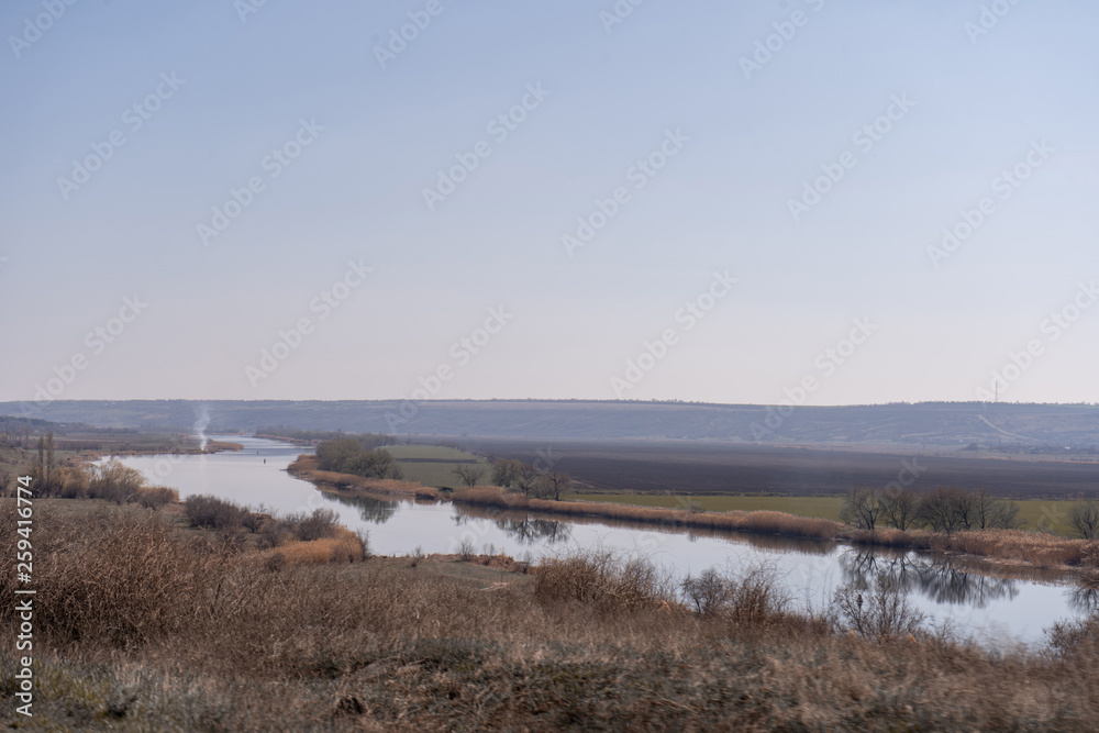 Picturesque landscape: river, hills and cloudless blue sky. Nature nackground