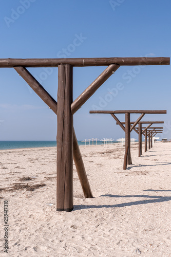 Vertical. Wooden brown umbrella supports stand in a row in the resort town by the sea in the spring in the off-season. 