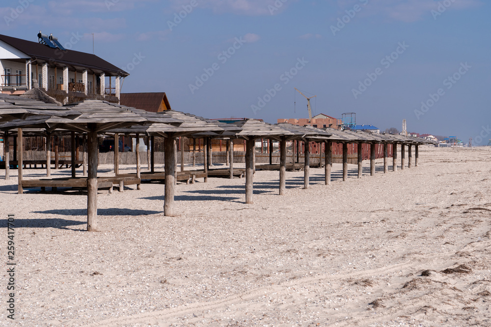 The resort town with wooden umbrellas on the sandy-beach seashore. 