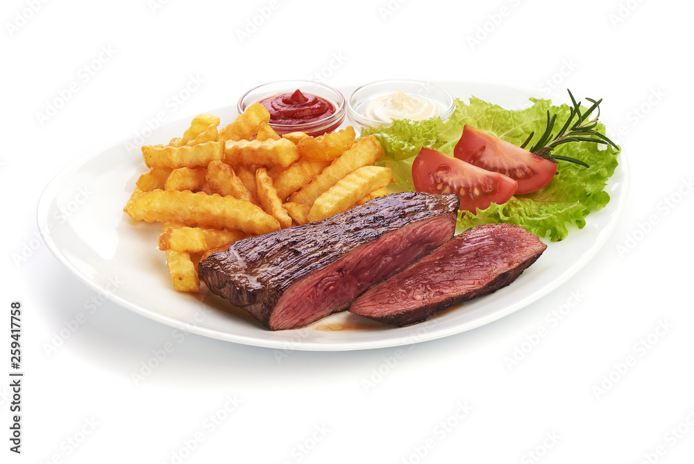 Grilled barbecue beef steak with french fries and vegetables, fried meat, close-up Grilled barbecue beef steak with french fries and vegetables, fried meat, close-up