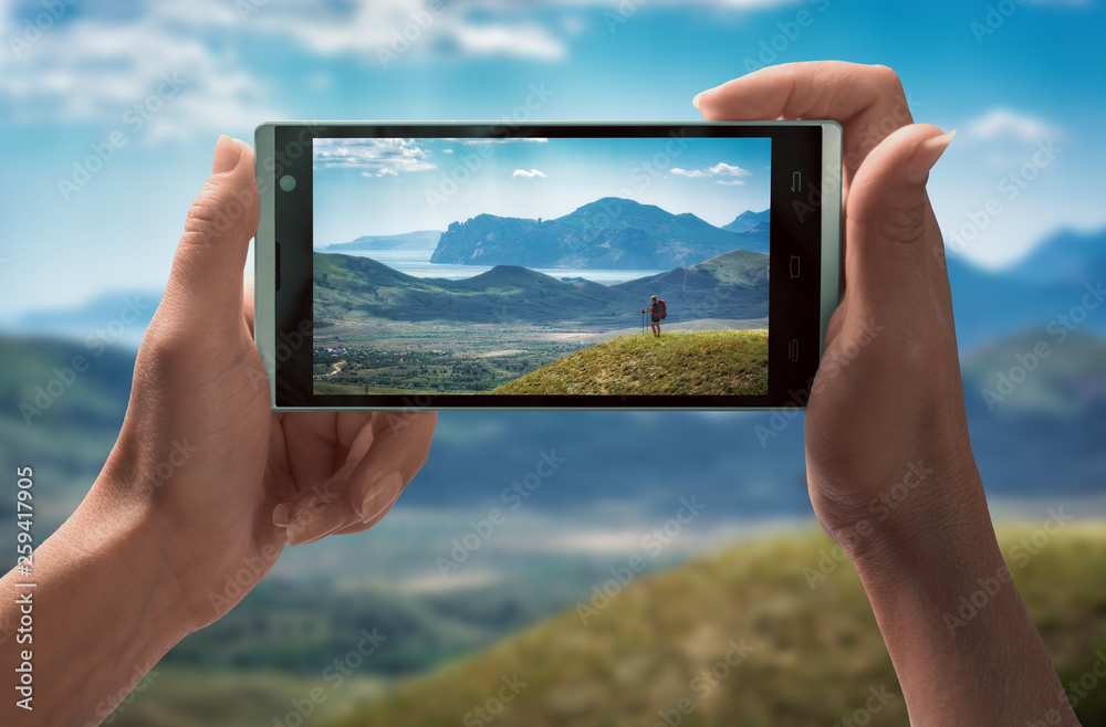 Girl hiker in a mountain valley on smartphone screen