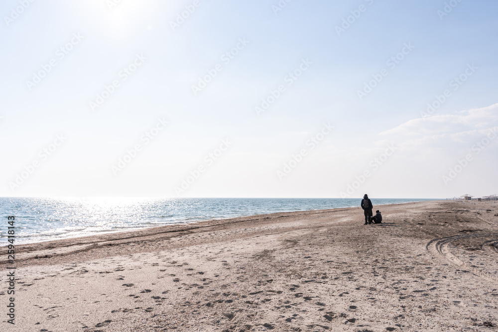 People sitting on the sandy-shell seashore in the afternoon during sunny weather in summer
