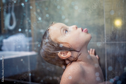 Blond girl playing under shower in bathroom