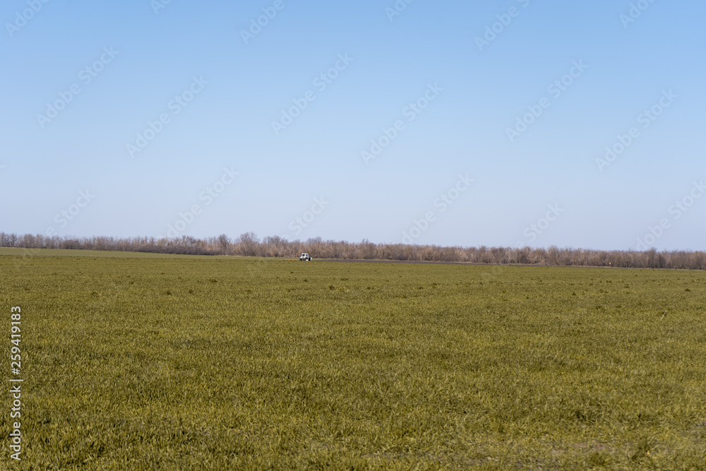 A small tractor in the distance in a spring green field in Ukraine