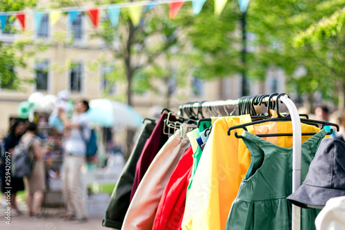 Clothes on the rail on the summer outdoor vintage fashion designer market. Garage sale, reuse the clothes, second hand and eco consumering