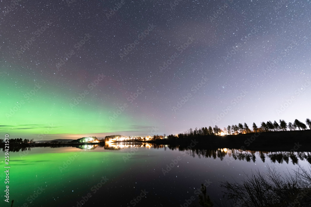 Aurora and stars reflecting at left side of the lake, forest reflection, night Scandinavian countryside, autumn
