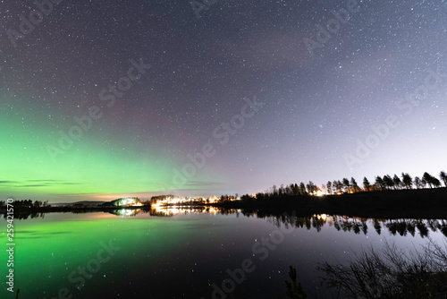 Aurora and stars reflecting at left side of the lake, forest reflection, night Scandinavian countryside, autumn