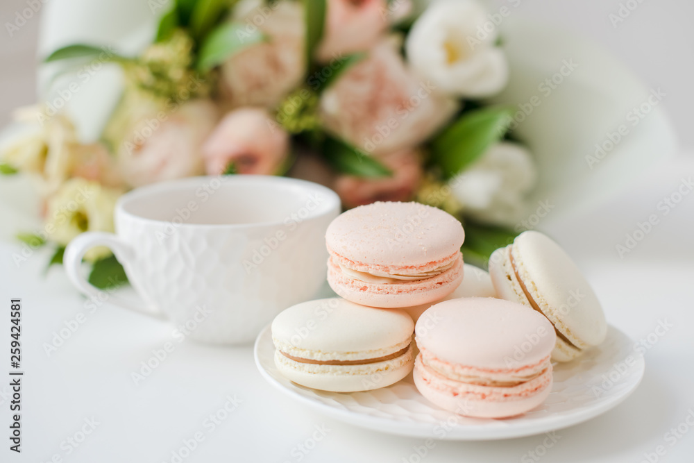 Elegant sweet dessert macarons, cup of coffee and pastel colored beige flowers bouquet Elegant sweet dessert macarons, cup of coffee and pastel colored beige flowers bouquet