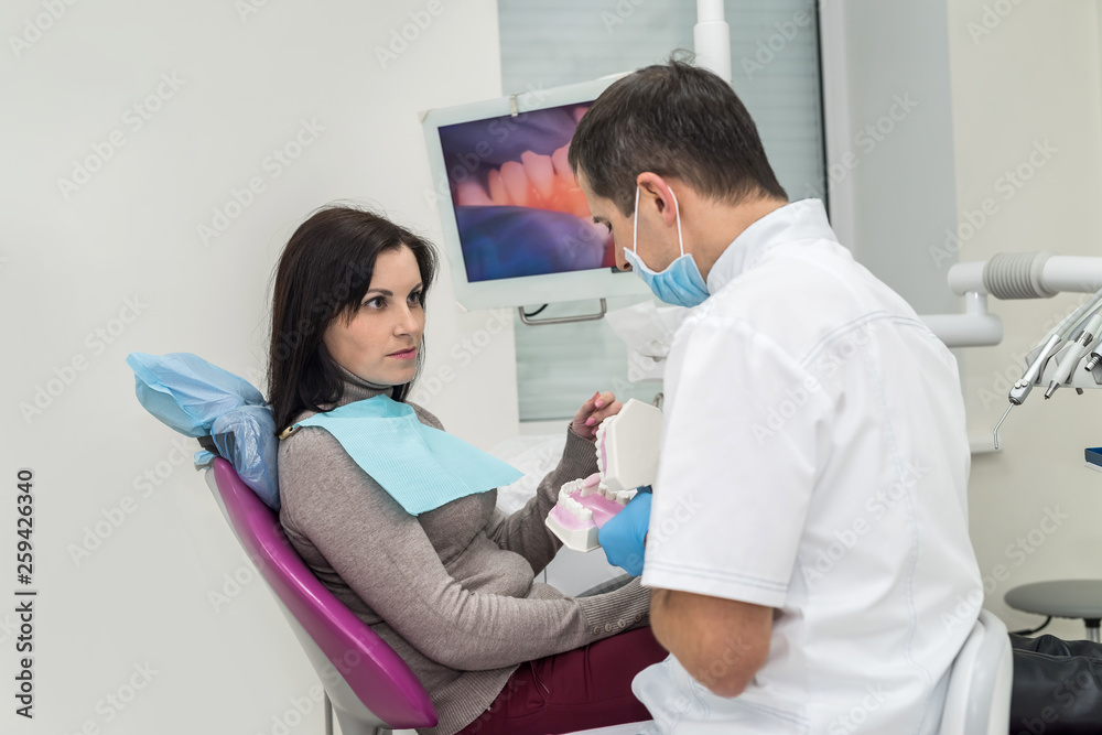 Doctor showing patient how clean teeth on jaw sample Doctor showing patient how clean teeth on jaw sample