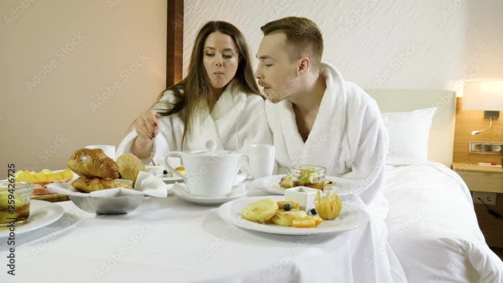 Loving couple having tasty breakfast, eating healthy food and drinking tea or coffee at luxury hotel. 4K Loving couple having tasty breakfast, eating healthy food and drinking tea or coffee at luxury hotel. 4K