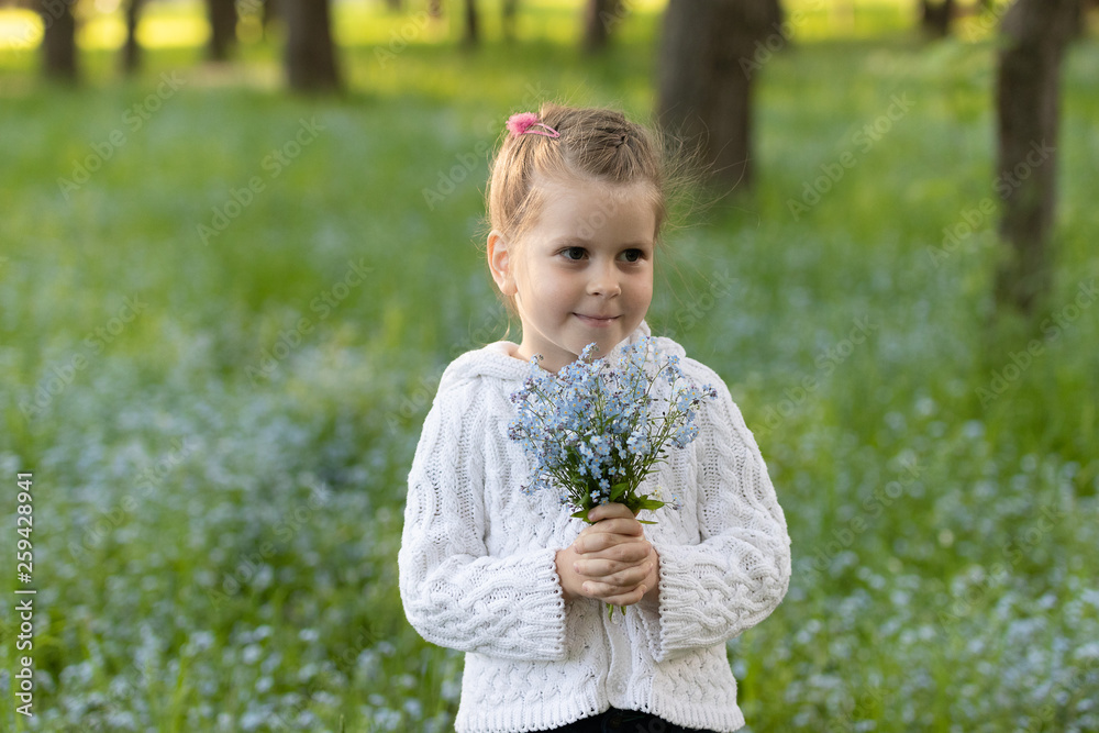 little girl with a bouquet of forget-me-nots in her hands on a flowered meadow in sunny day little girl with a bouquet of forget-me-nots in her hands on a flowered meadow in sunny day