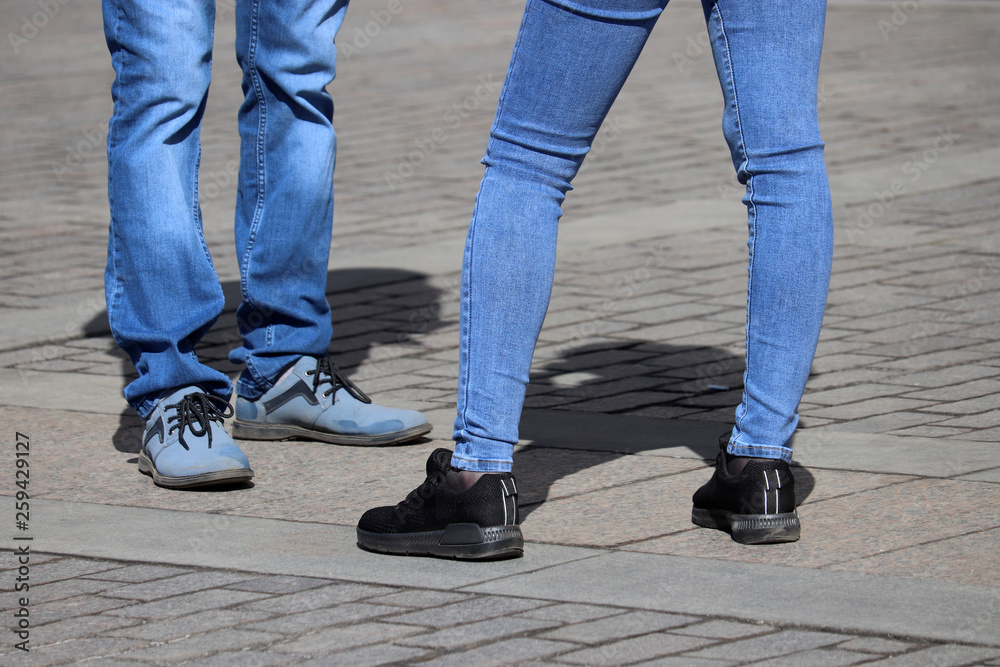 Couple wearing jeans stands on the street. Male and female legs on sidewalk, denim fashion Couple wearing jeans stands on the street. Male and female legs on sidewalk, denim fashion