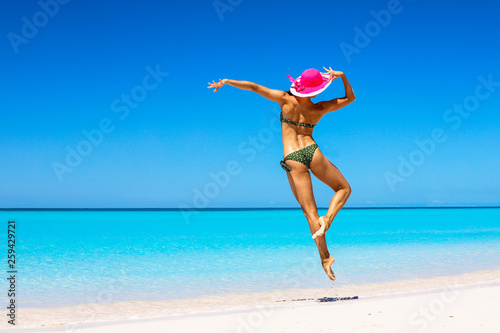 Beautiful girl in a pink hat in a gracegul jump on the beach in Bahamas. Outdoor shot.