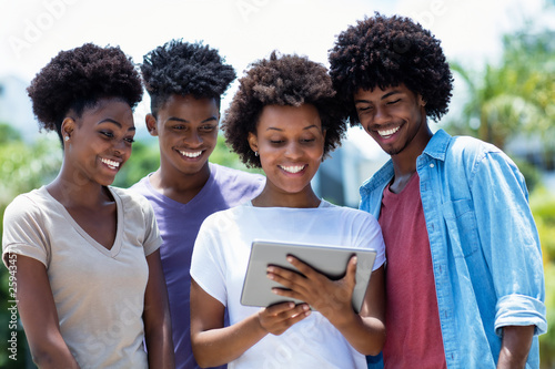 Group of african american young adults reading news with digital tablet