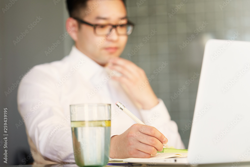 Young Asian businessman is working on laptop in office Young Asian businessman is working on laptop in office