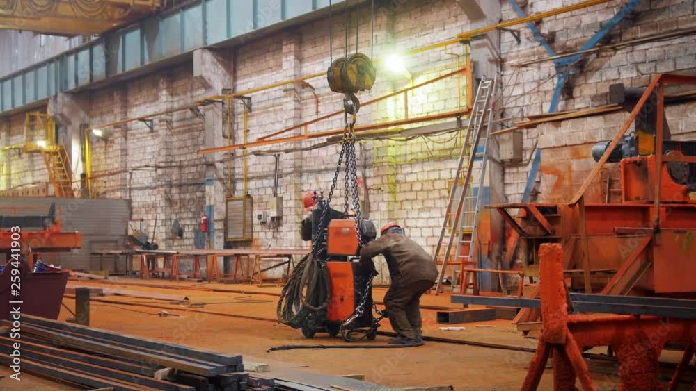 Industrial concept. A crane put down the orange detail on the floor and man worker taking it Industrial concept. A crane put down the orange detail on the floor and man worker taking it